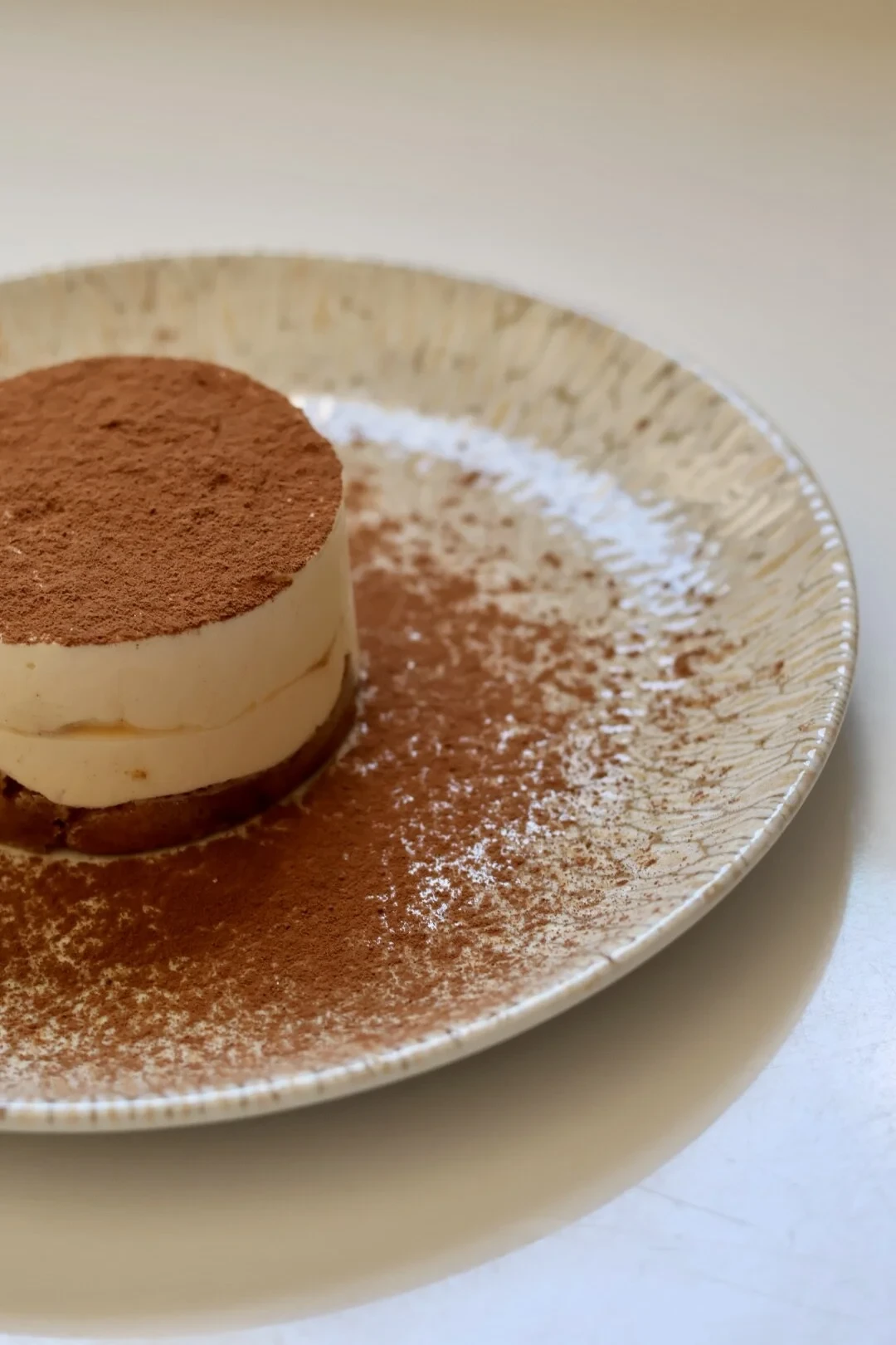 Tiramisu en portion sur assiette saupoudré de cacao
